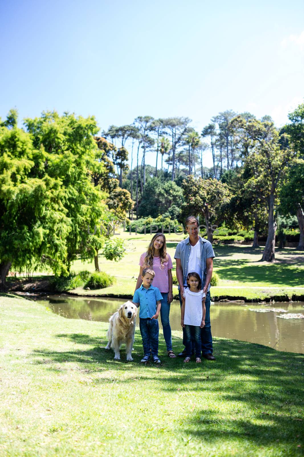 Happy family standing in the park  by Wavebreakmedia