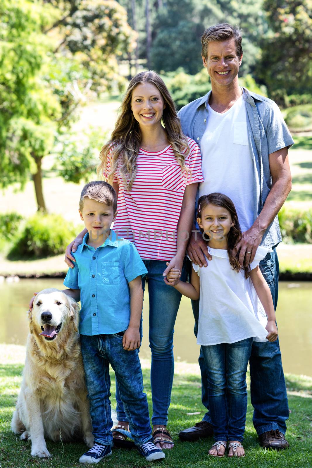 Portrait of a happy family standing in the park with their dog