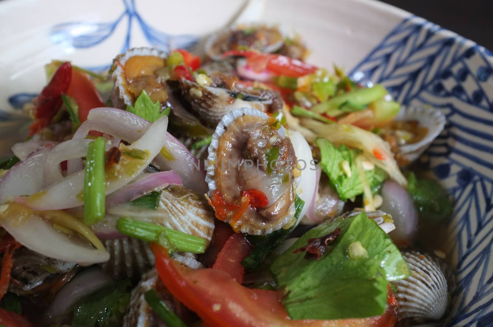 CLOSE UP view , Cockles salad / Hot and spicy shellfish blood cockles salad mix vegetable tomato herb and spices , thai style food