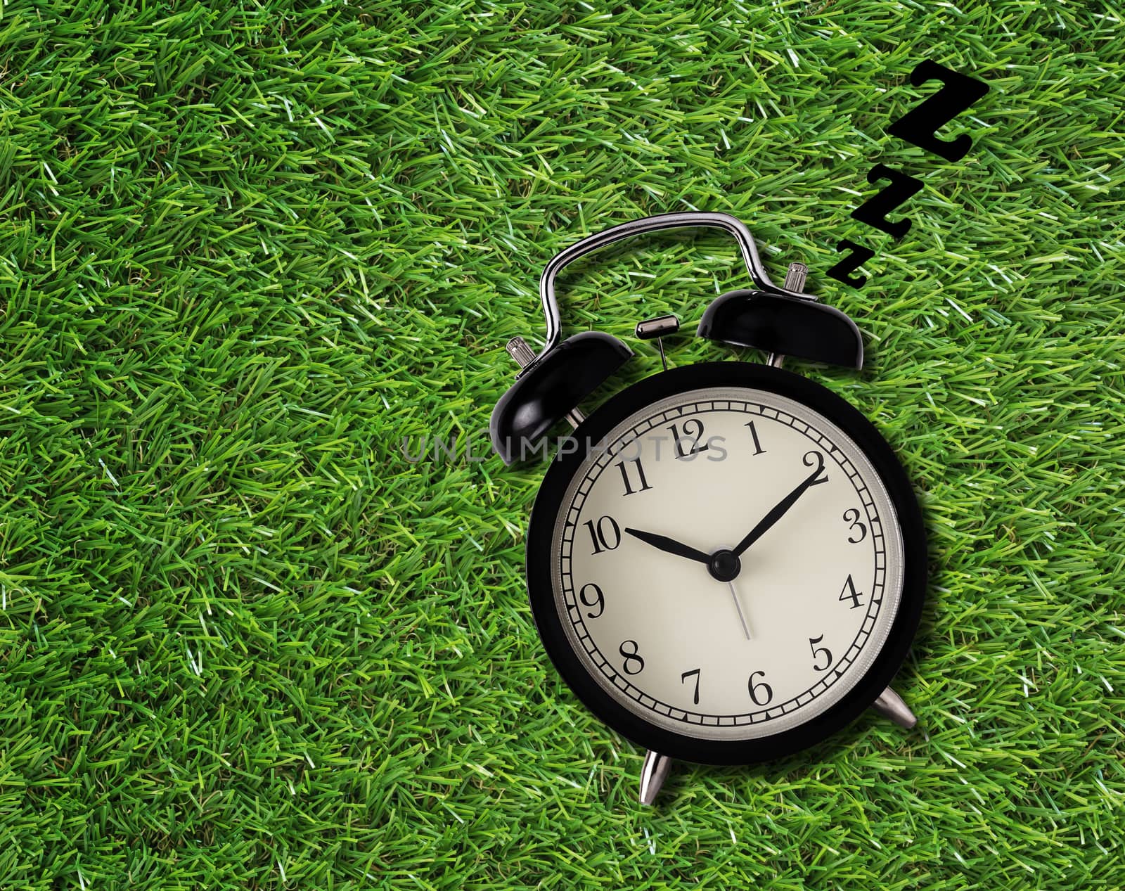 Wake up late concept, alarm clock sleep on green grass background