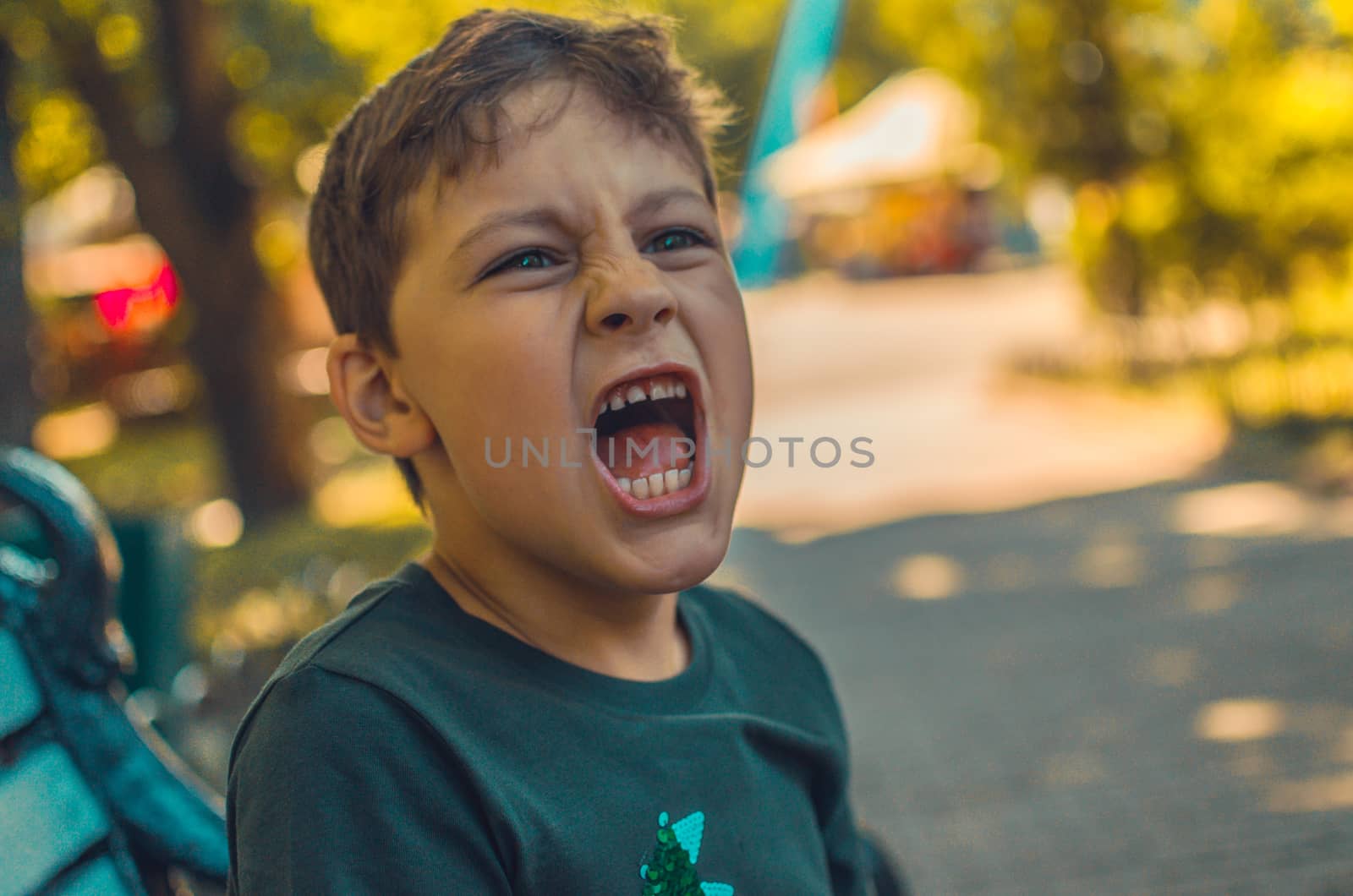 beautiful boy screams in a city park