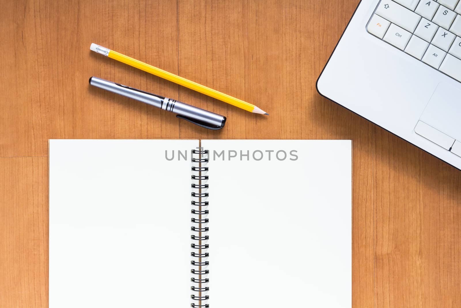 Blank notebook and computer with pen and pencil on wood table, business concept