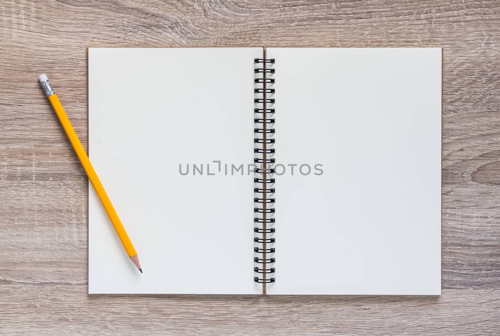 Blank notebook and yellow pencil on wooden table