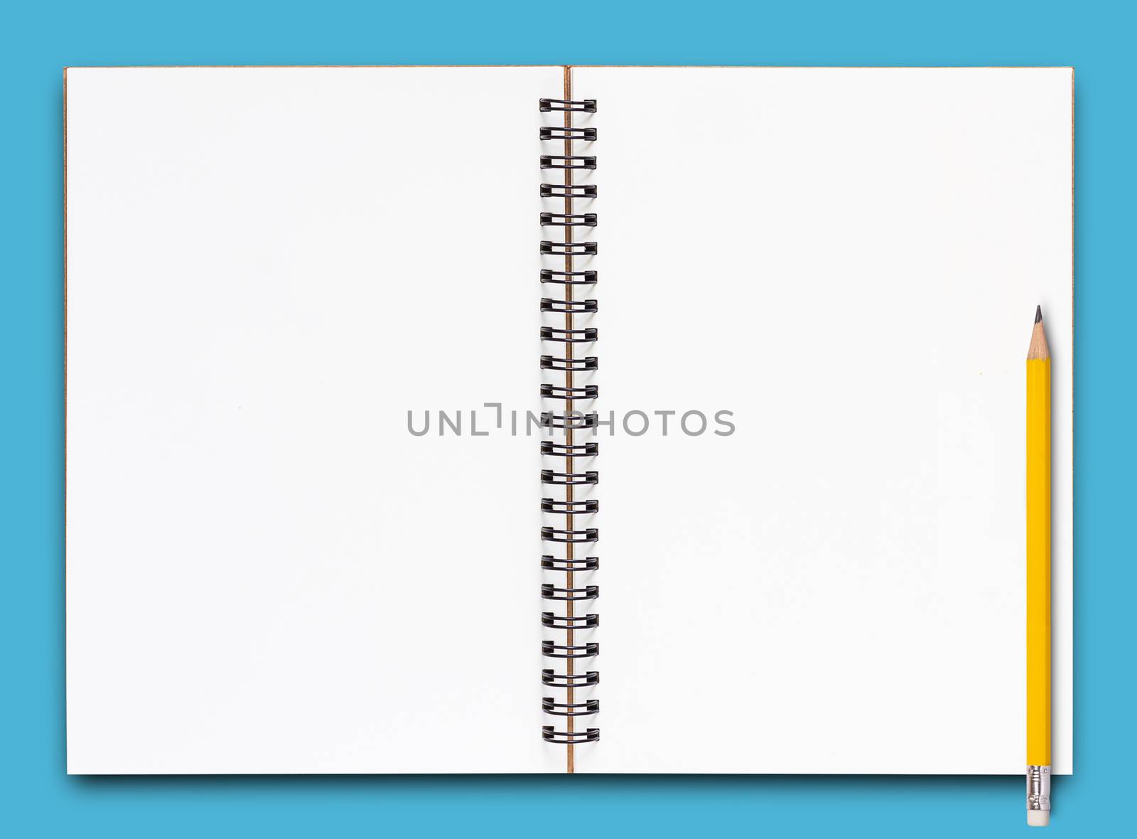 Open notebook and yellow pencil on blue background
