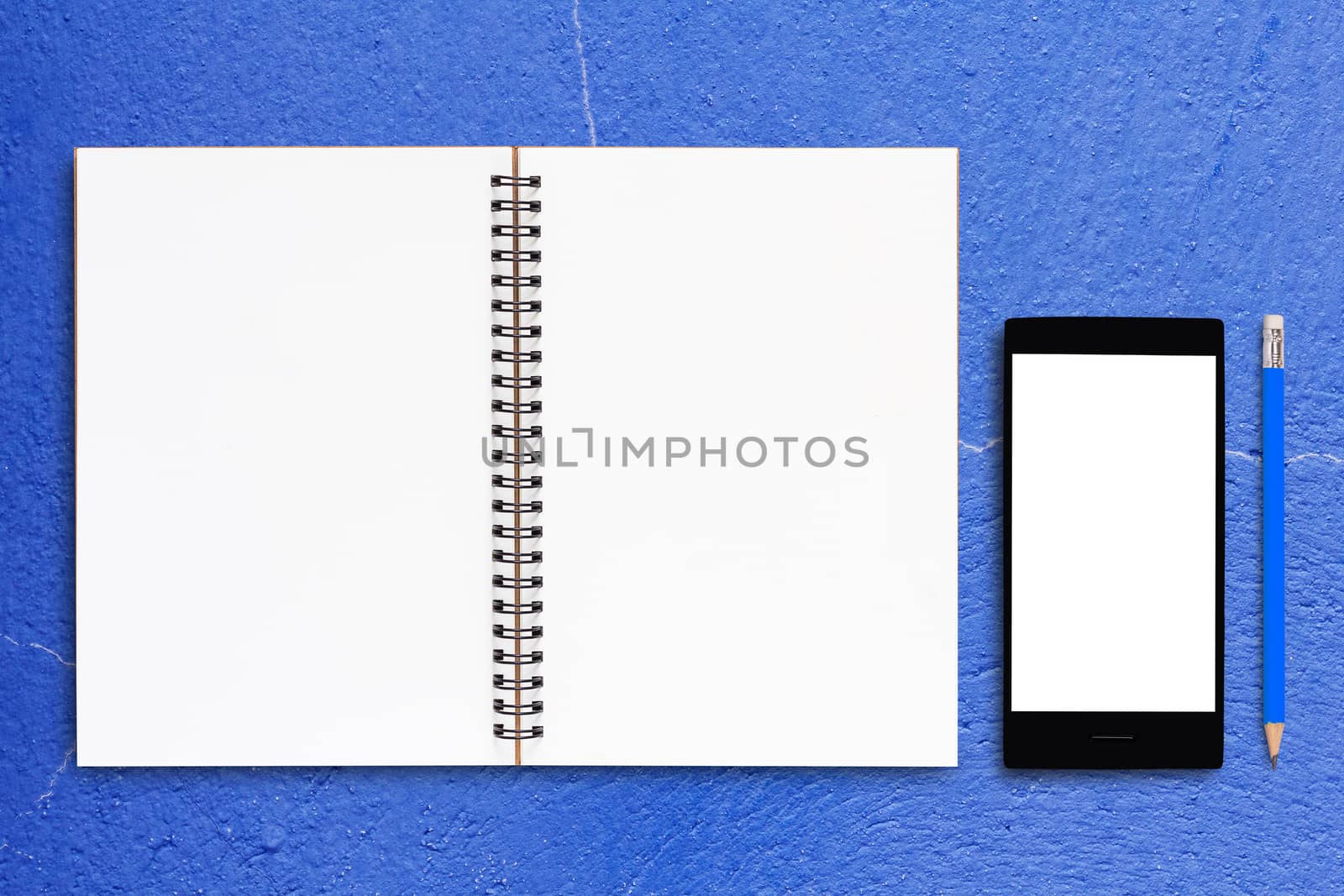 Notebook and mobile phone on blue background, business concept
