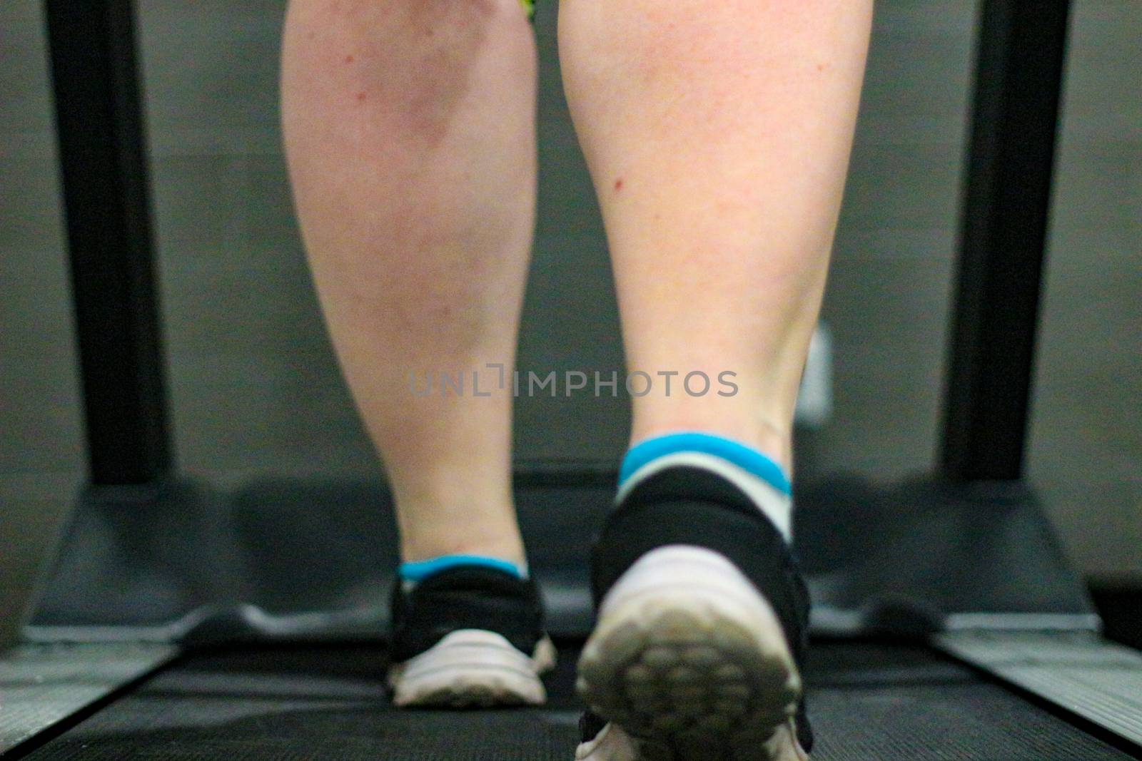 Female athlete legs walking treadmill machine, cardio exercise, active lifestyle. Stock photo
