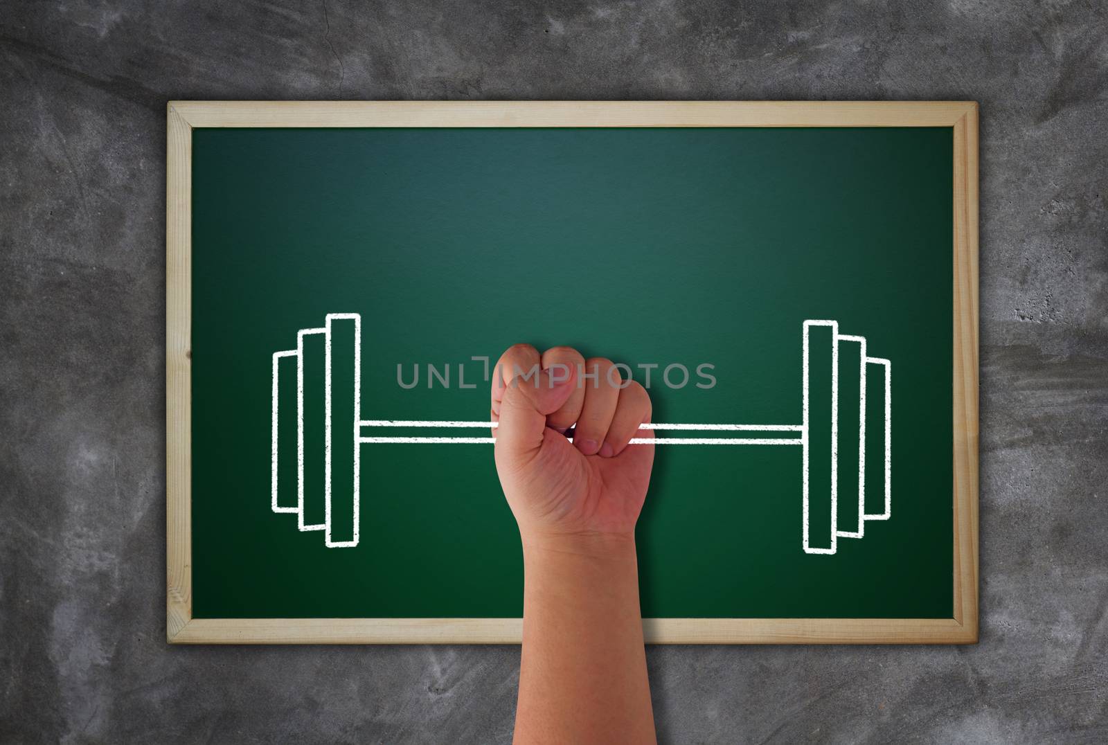 Business success concept, hand and weight lifting target to growth and achievement on blackboard background