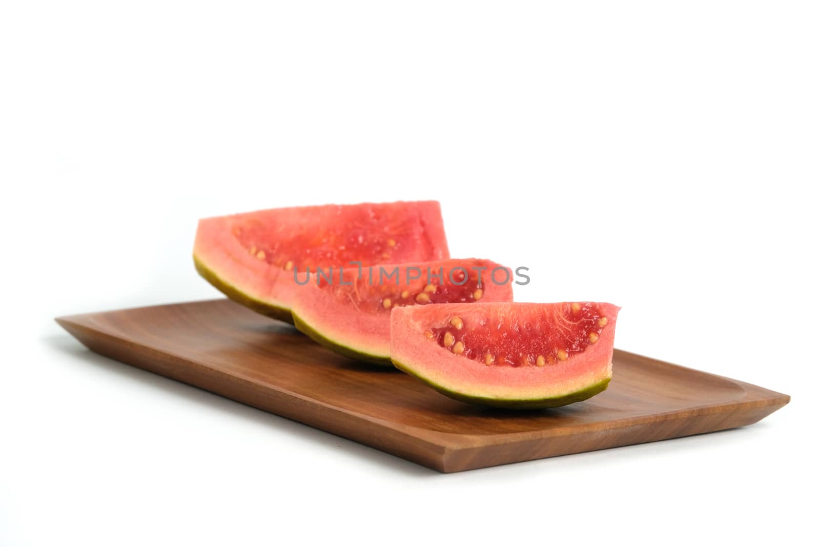 Fresh Psidium guajava / common guava / lemon guava sliced fruit on a wooden plate isolated on a white background