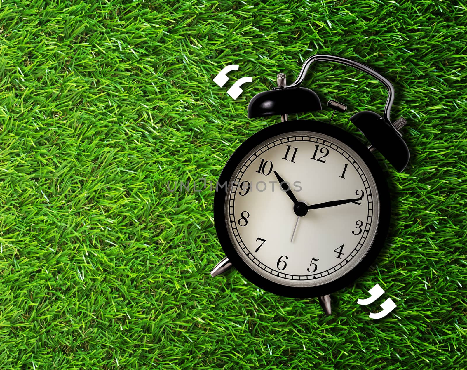 Time management concept, business planning, alarm clock on green grass background