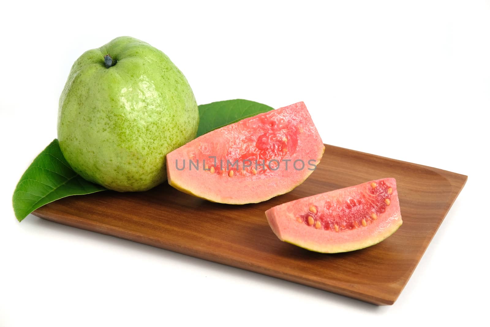 Fresh Psidium guajava / common guava / lemon guava sliced and raw fruit on a wooden plate isolated on a white background