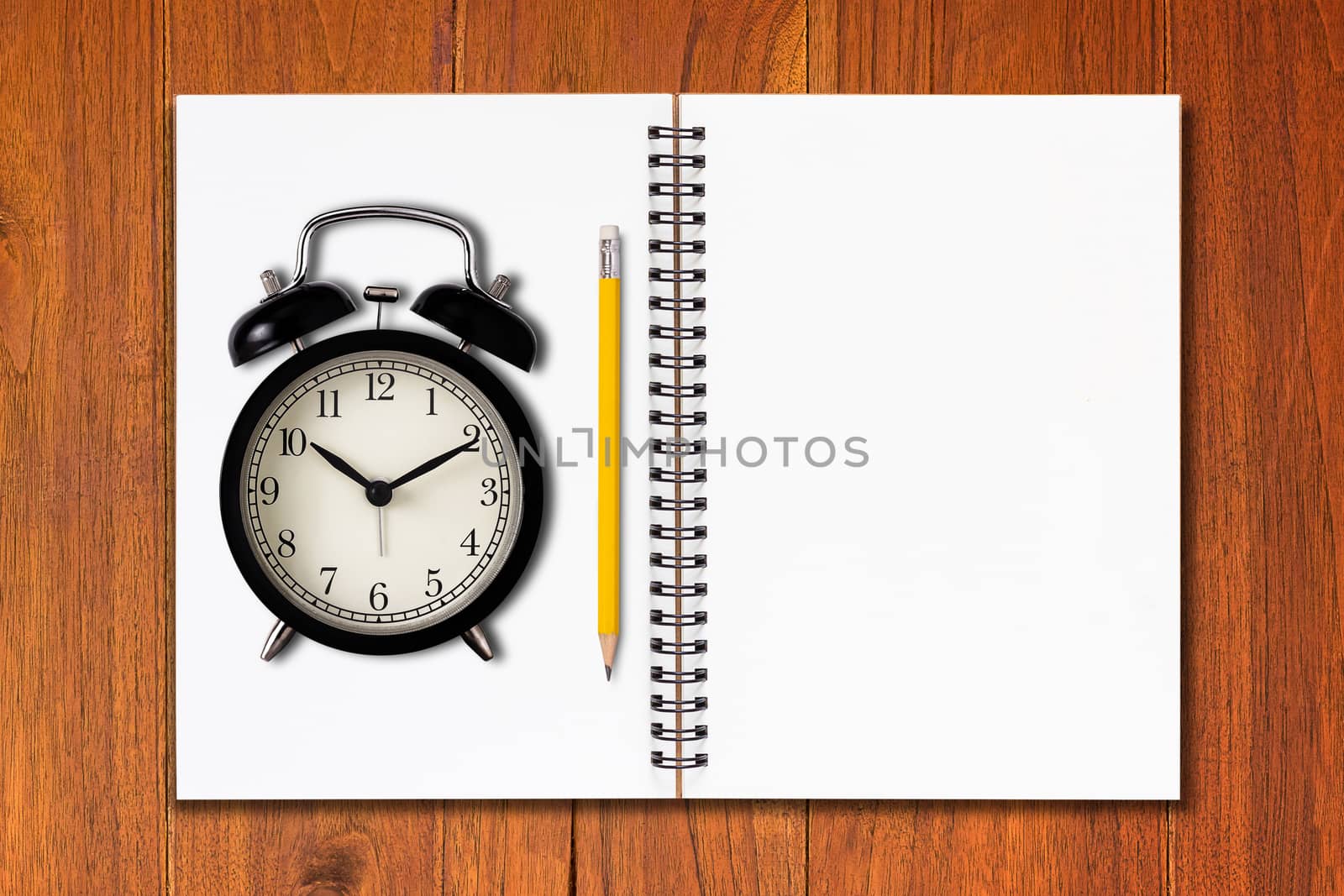 Time management concept, business planning, open notebook and alarm clock on wood table