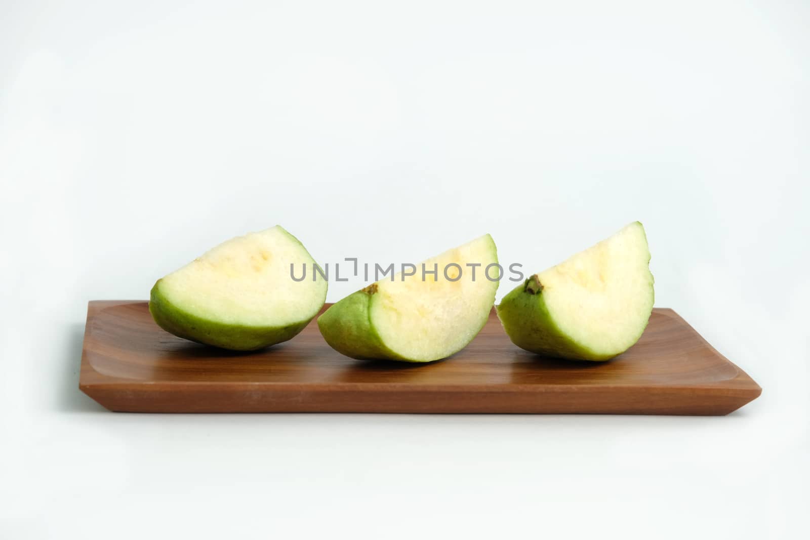 sliced green crystal guava raw fruit on a wooden plate isolated on a white background