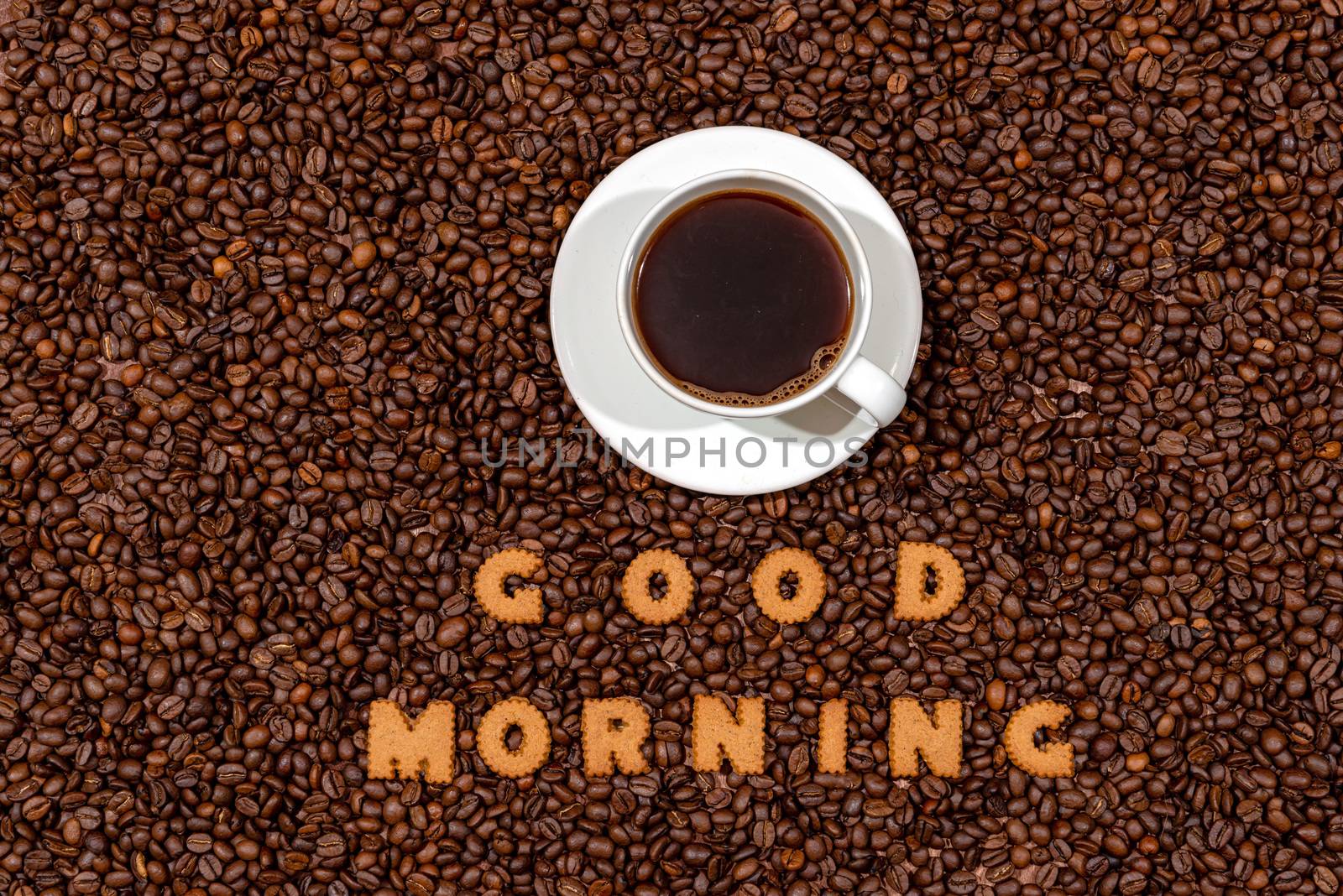 White caffee mug and words GOOD MORNING made from biscuit letters on a dark coffee bean background - image