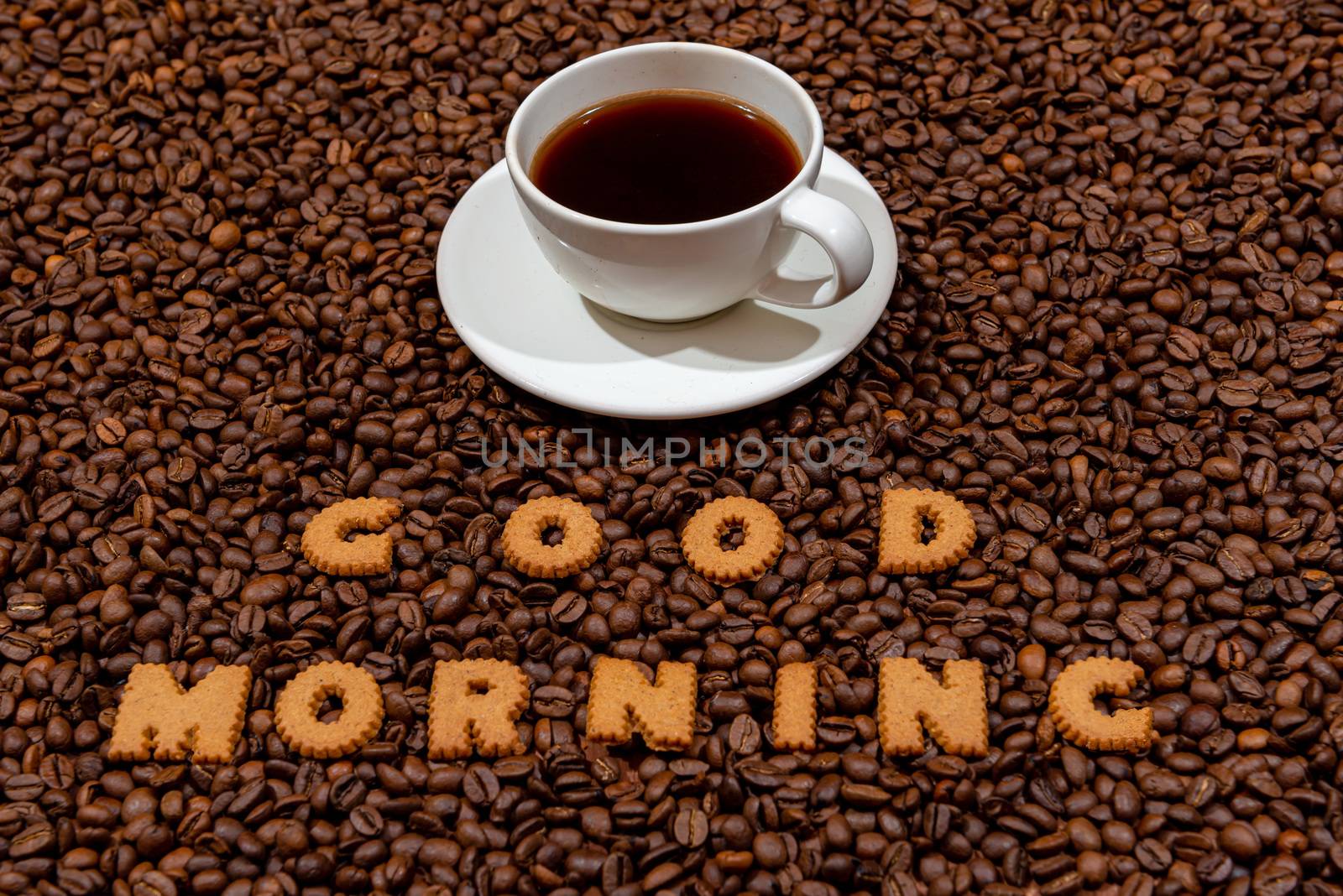 White caffee mug and words GOOD MORNING made from biscuit letters on a dark coffee bean background - image