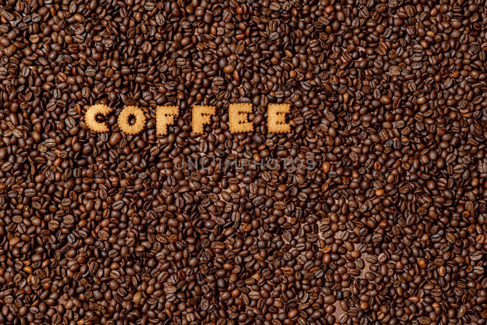 The word COFFEE  made from biscuit letters on a dark coffee bean background - image