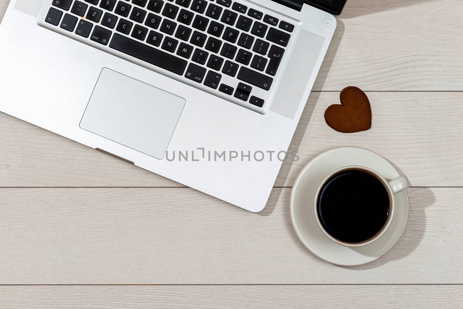 Flat lay, top view wooden office desk. Workspace with laptop, caffe cup and gingerbread heart - image