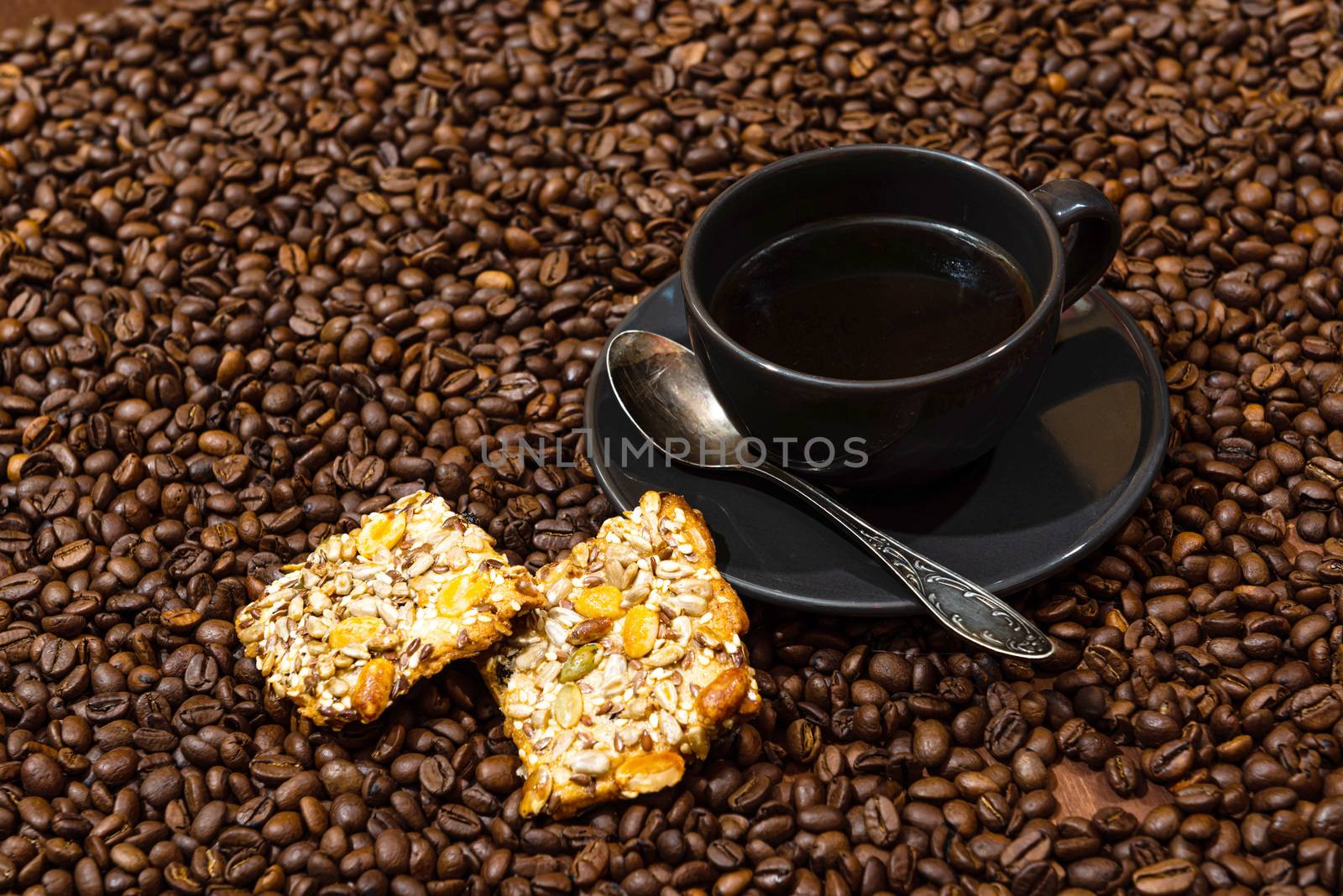 Black coffee mug and cookies on the coffee beans background - image