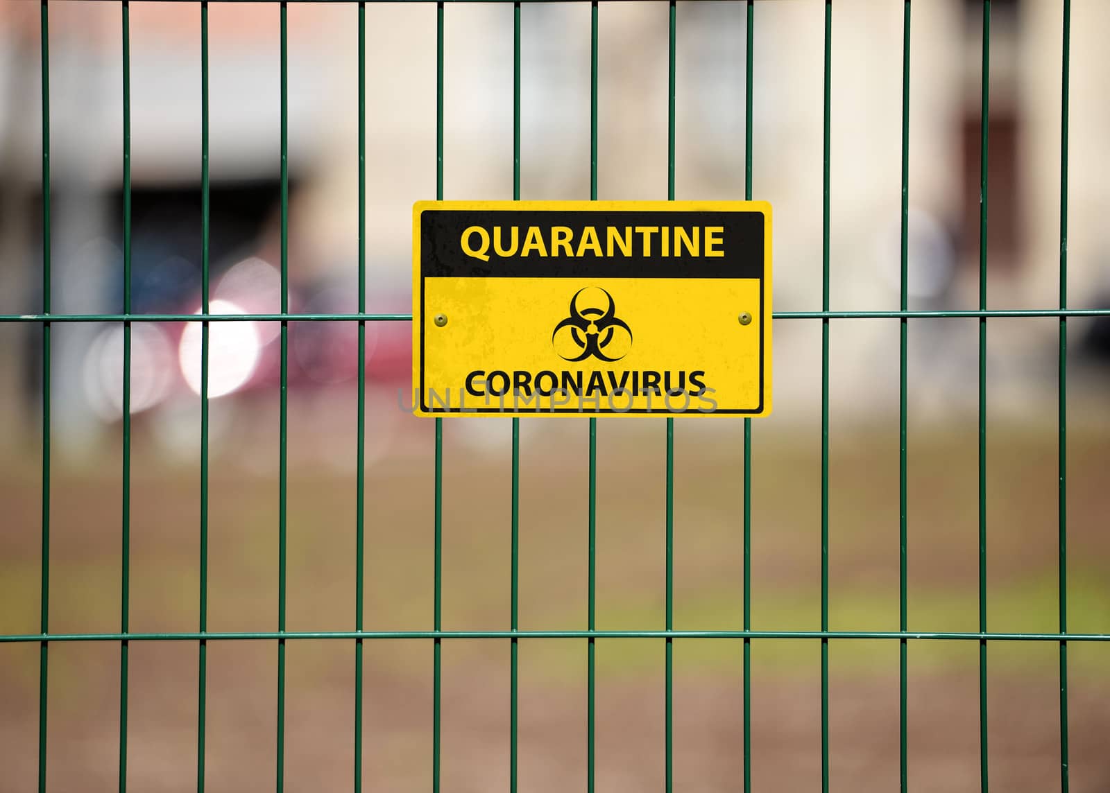 Coronavirus Quarantine sign on green decorative metal wire fence, the city street silhouettes are visible behind the fence