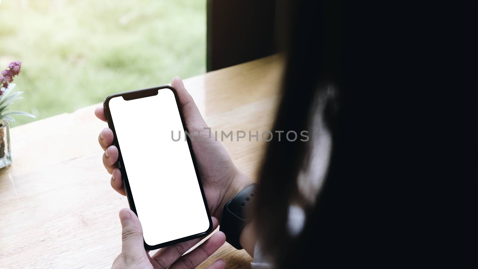 Mockup image of woman's hands holding white mobile phone with blank screen.
