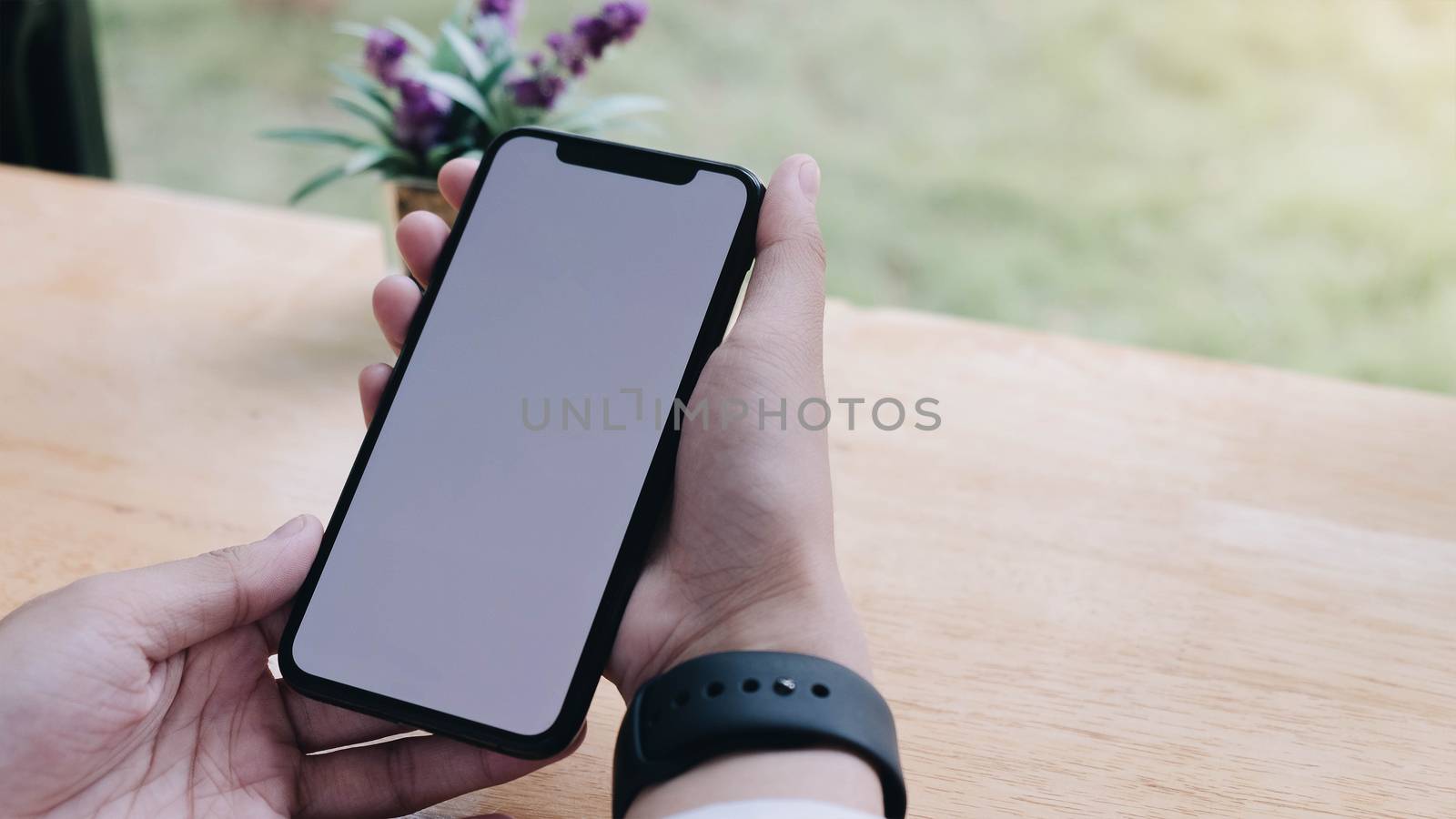 Close-up view of woman's hands holding blank screen smartphone by wichayada