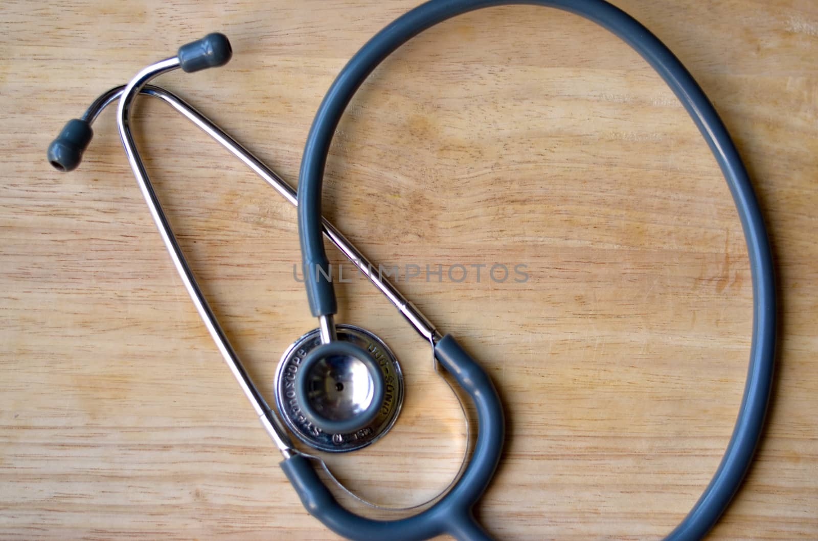 Flat layout of a stethoscope placed on a wooden table backgound. Doctors use this instrument to hear the hearbeats and pulse to diagnose any illness in his examination