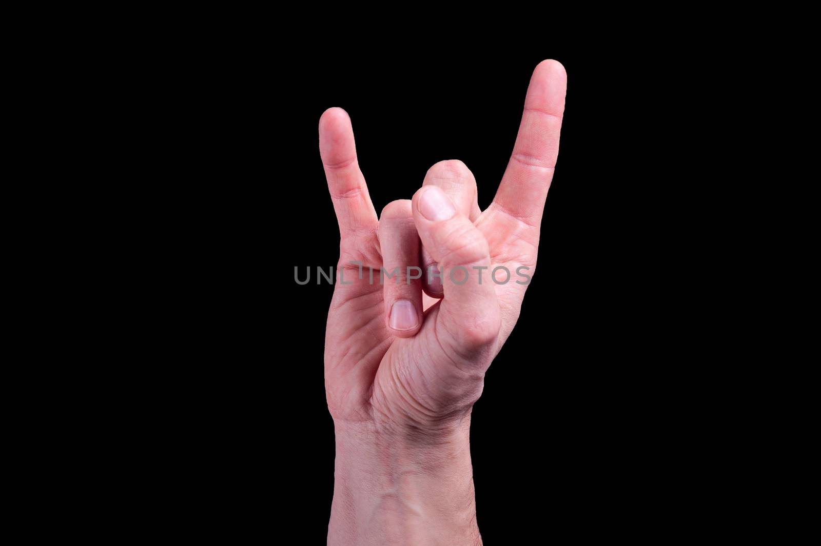 Hand of euroopean human shows the sign of the horns on isolated black background