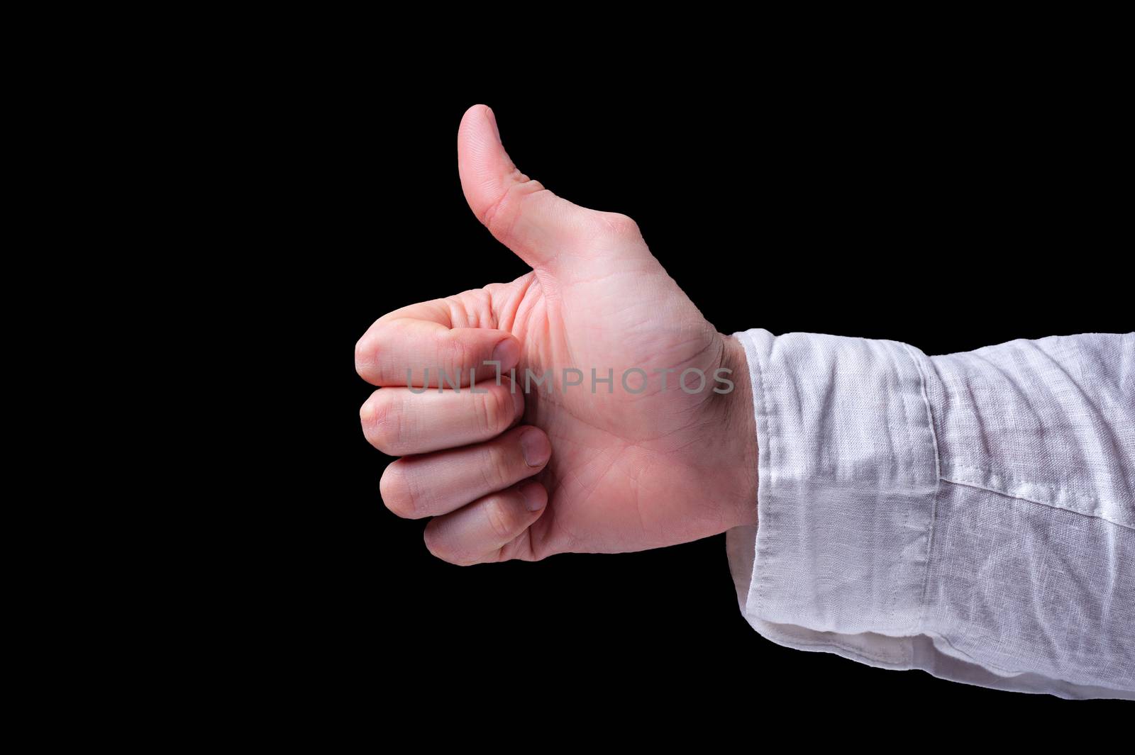 The human hand in a white shirt shows thumb signal, usually described as a thumbs-up sign on isolated black background