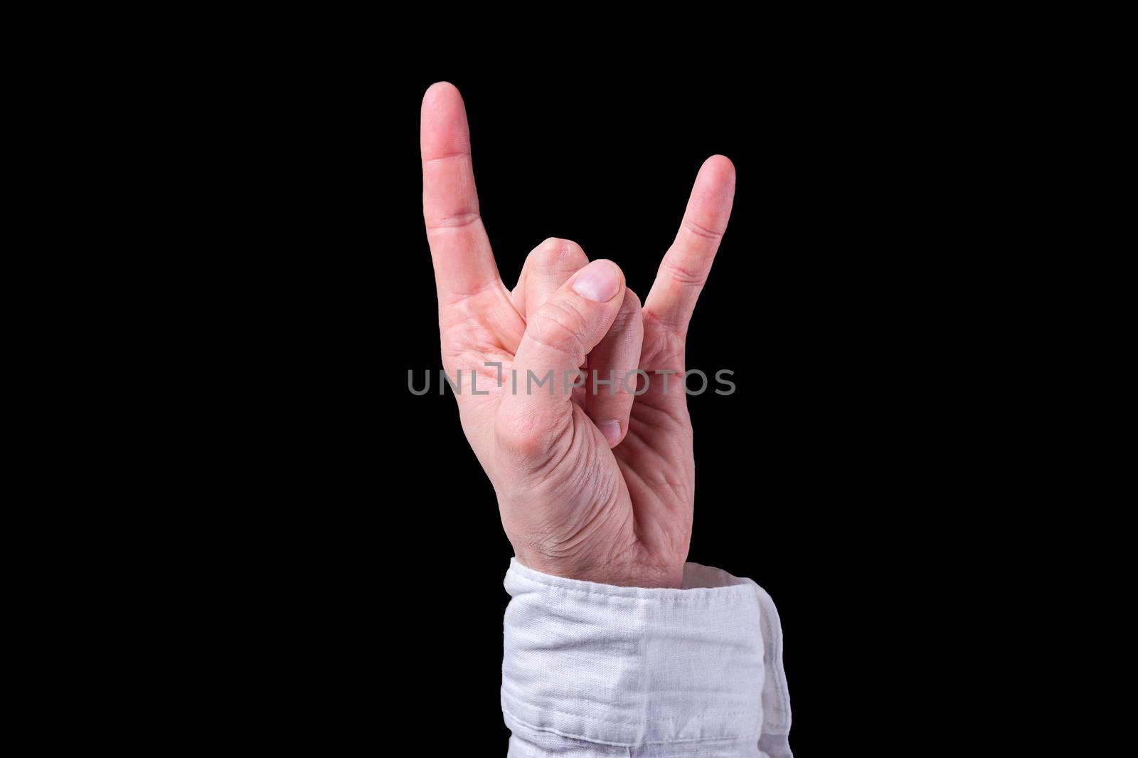 Human hand in a white shirt shows The sign of the horns on isolated black background