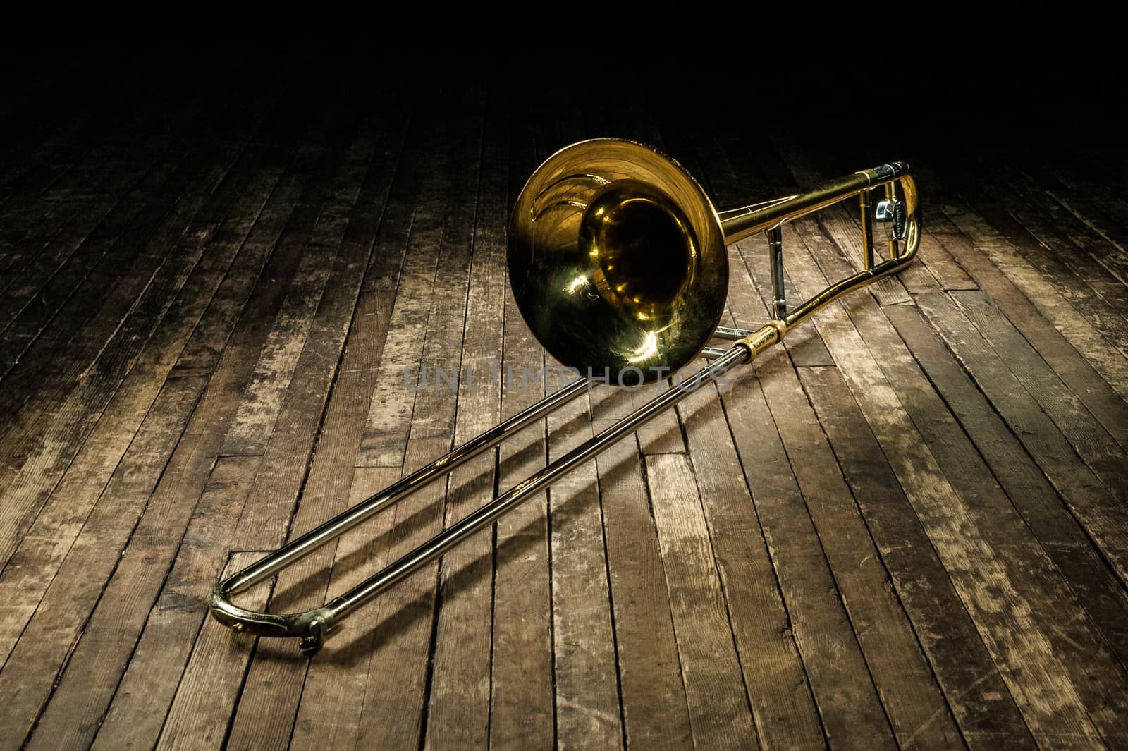 golden brass instrument trombone lies on a brown wooden stage