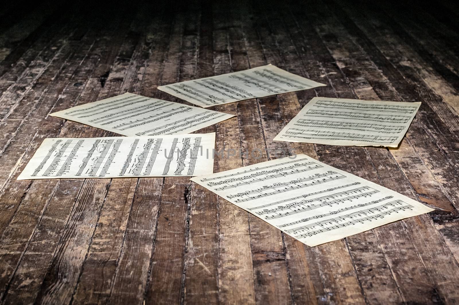 music sheets with notes of a musical work lie on the old floor in the dark