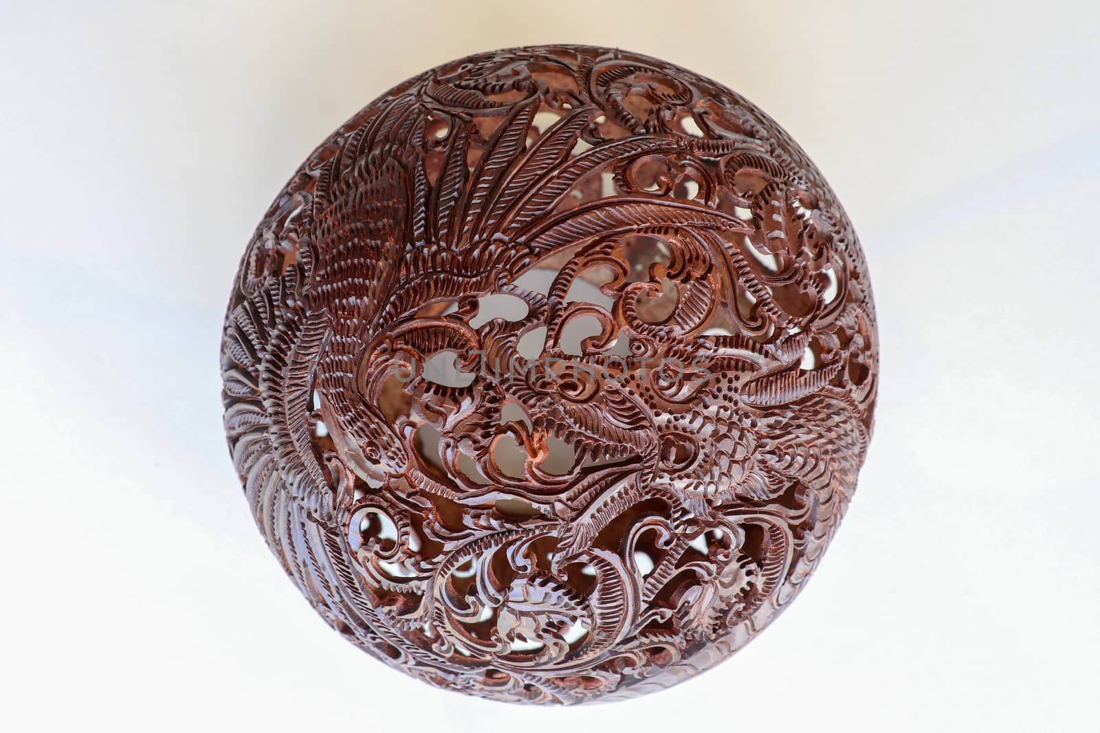 Close up ornamental shell for candle. Carved Souvenir from Coconut. Traditional handicraft on Bali, Indonesia. Hand carved ornaments with animal and plant motifs on the coconut shell. Mystical dragon.