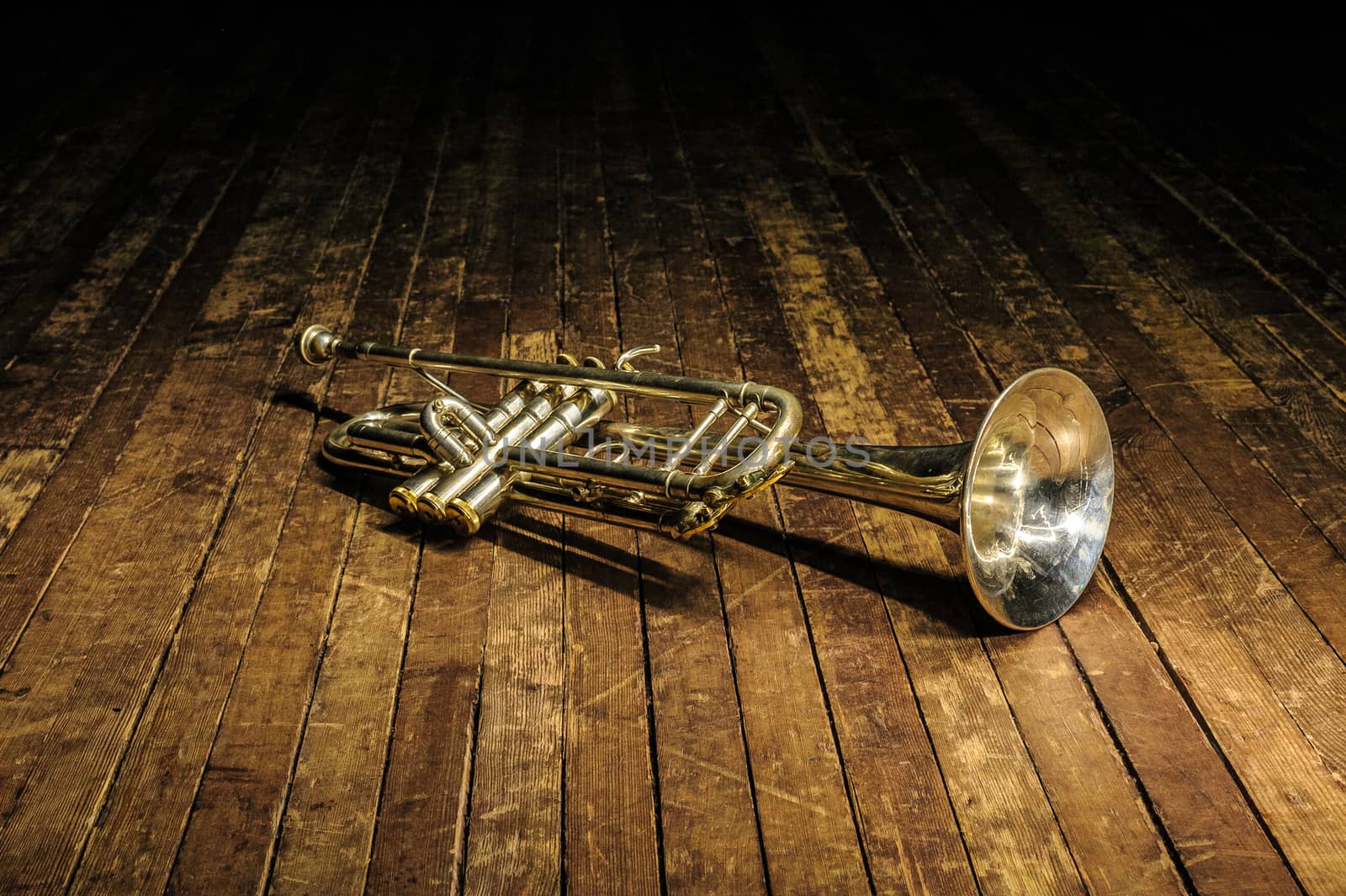 white brass trumpet lies on a wooden stage