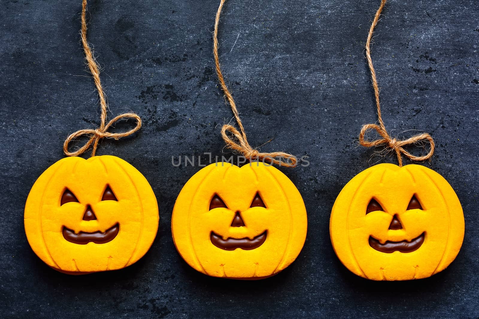 Halloween cookies with pumpkin shape on blackboard.