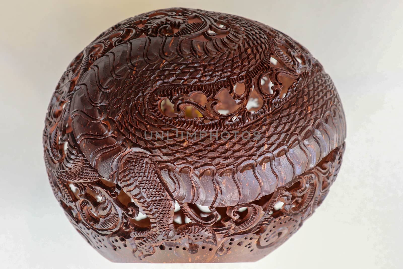 Close up ornamental shell for candle. Carved Souvenir from Coconut. Traditional handicraft on Bali, Indonesia. Hand carved ornaments with animal and plant motifs on the coconut shell. Mystical dragon.