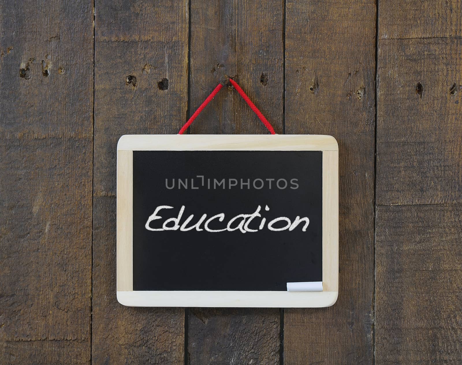 Blackboard hanging on a old wooden wall with word Education.