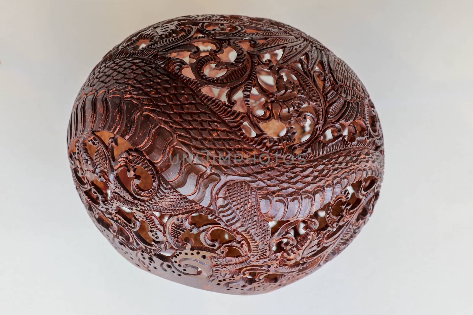 Close up ornamental shell for candle. Carved Souvenir from Coconut. Traditional handicraft on Bali, Indonesia. Hand carved ornaments with animal and plant motifs on the coconut shell. Mystical dragon.