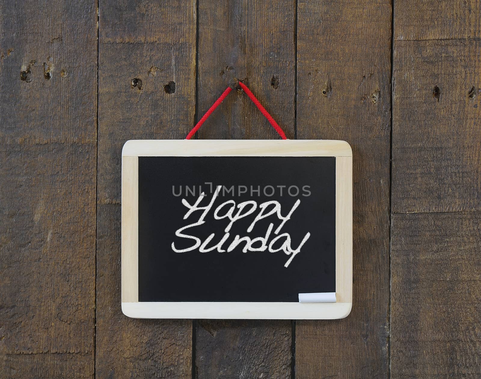 Blackboard hanging on a old wooden wall with phrase Happy Sunday.