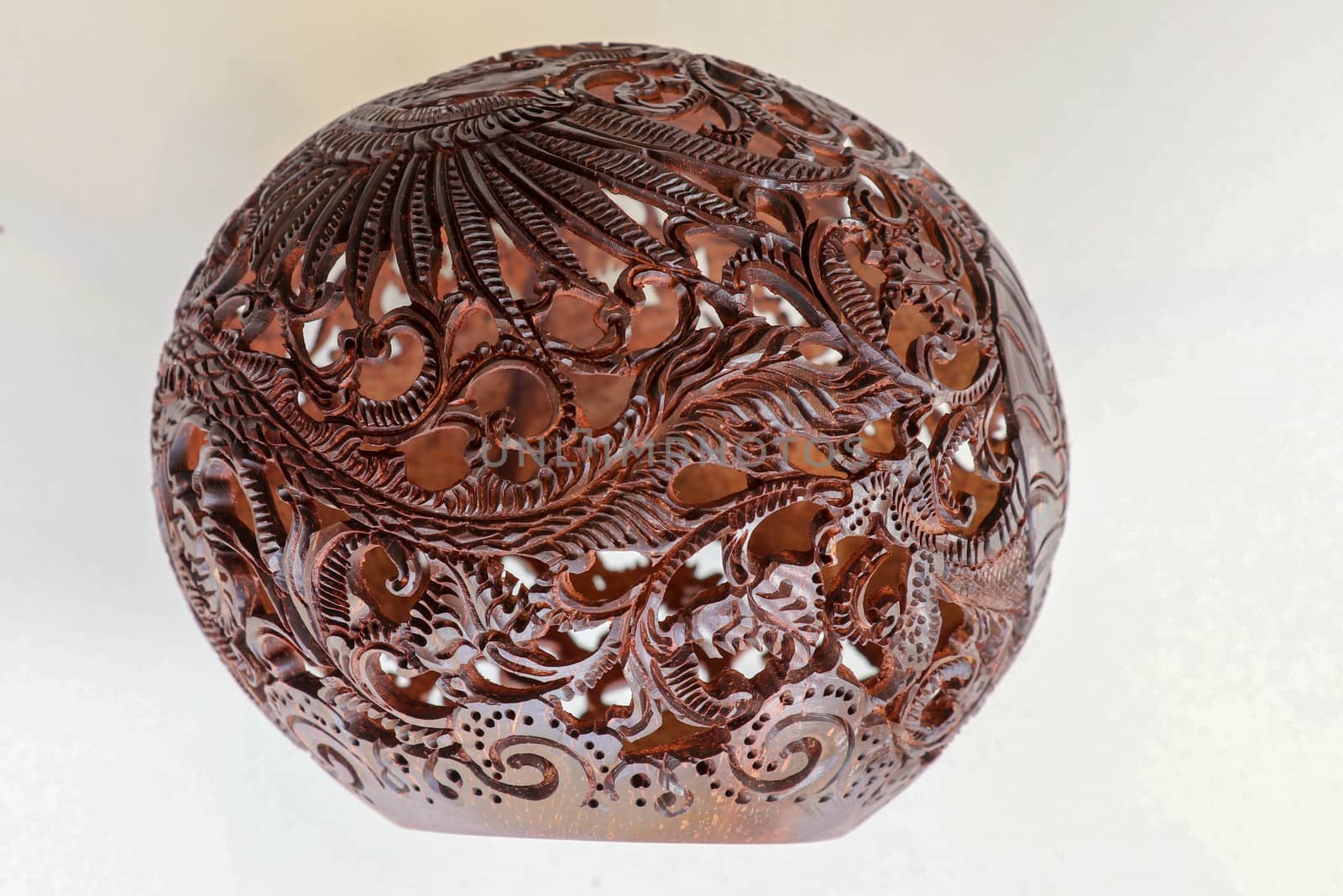 Close up ornamental shell for candle. Carved Souvenir from Coconut. Traditional handicraft on Bali, Indonesia. Hand carved ornaments with animal and plant motifs on the coconut shell. Mystical dragon.