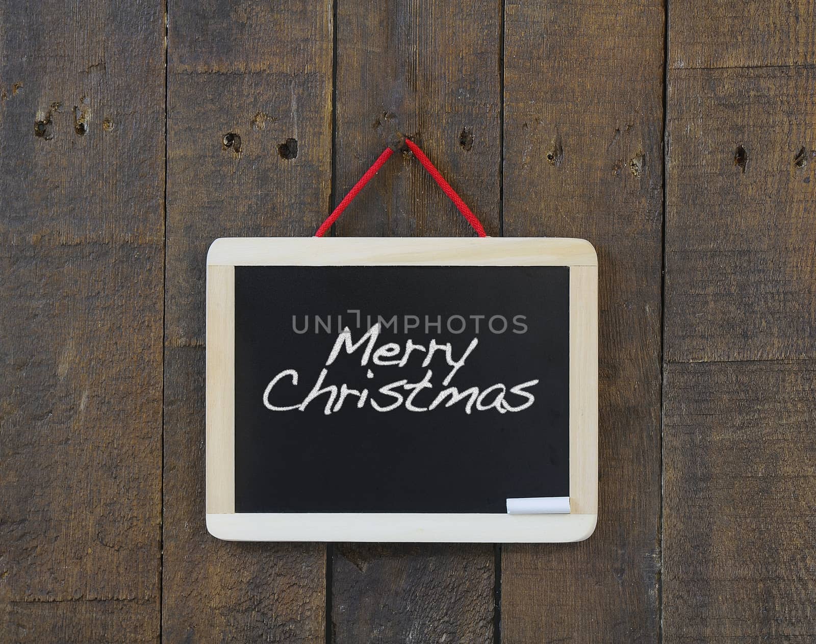 Blackboard hanging on a old wooden wall with Merry Christmas.