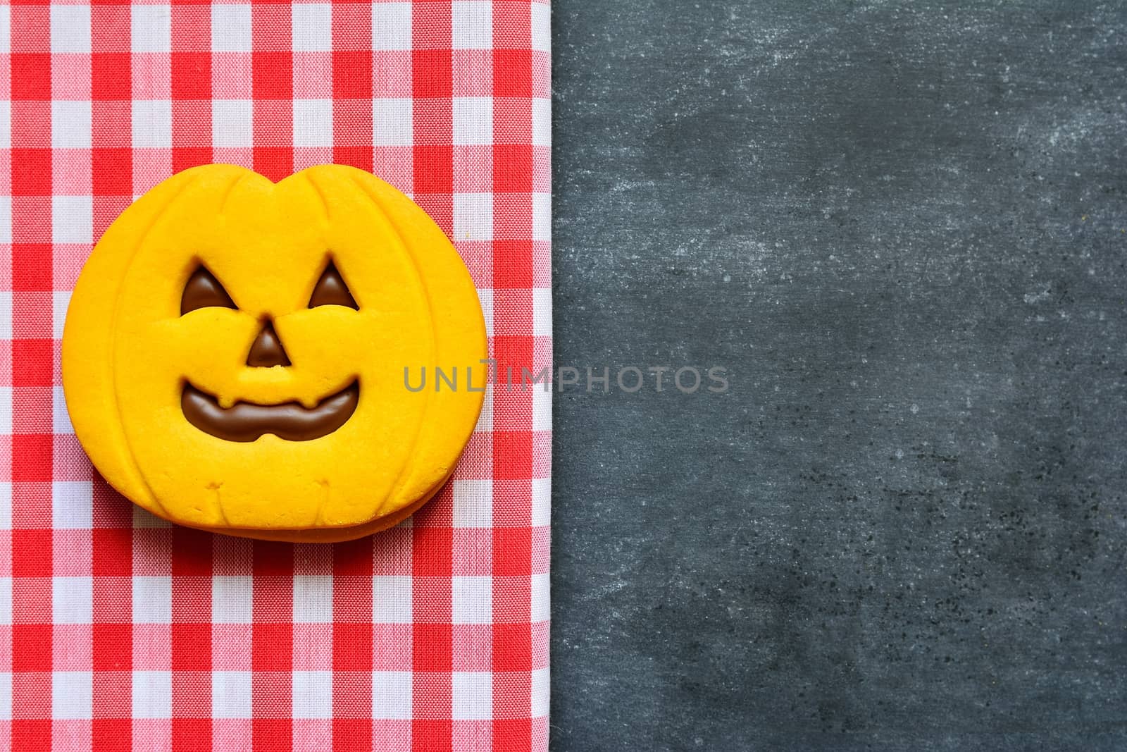 Halloween cookies with pumpkin shape on blackboard.