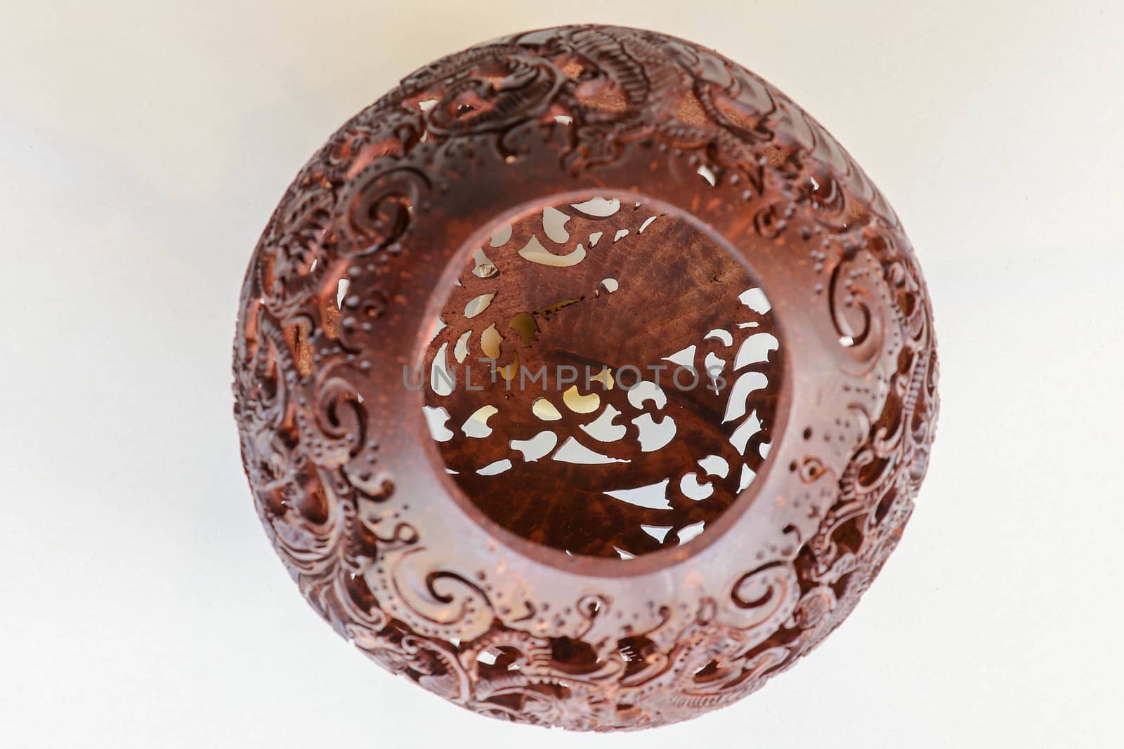 Close up ornamental shell for candle. Carved Souvenir from Coconut. Traditional handicraft on Bali, Indonesia. Hand carved ornaments with animal and plant motifs on the coconut shell. Mystical dragon.