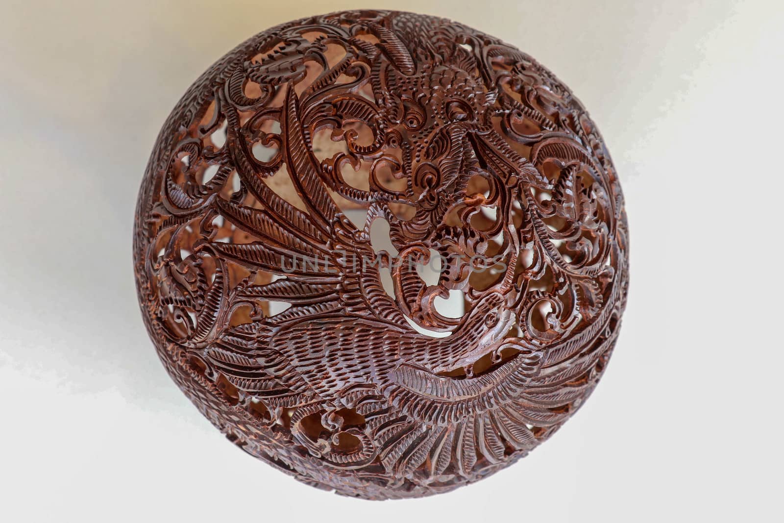 Close up ornamental shell for candle. Carved Souvenir from Coconut. Traditional handicraft on Bali, Indonesia. Hand carved ornaments with animal and plant motifs on the coconut shell. Mystical dragon.