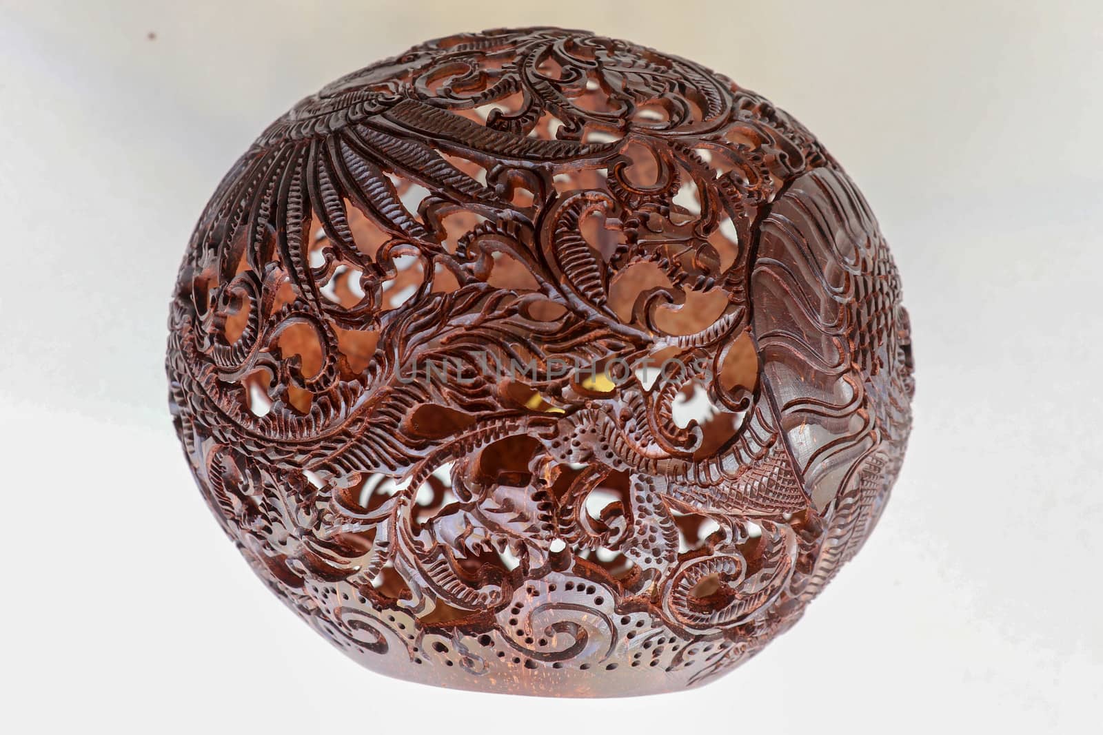 Close up ornamental shell for candle. Carved Souvenir from Coconut. Traditional handicraft on Bali, Indonesia. Hand carved ornaments with animal and plant motifs on the coconut shell. Mystical dragon.