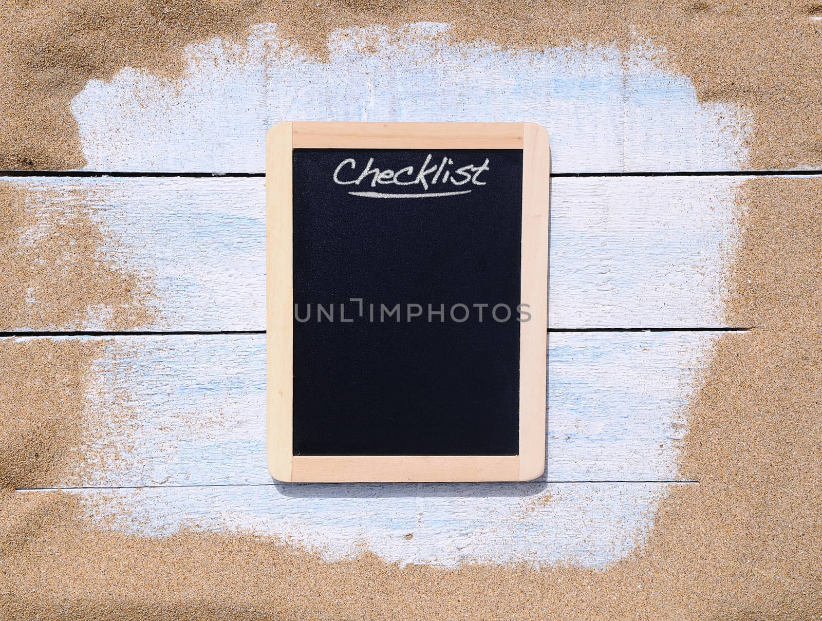 Blackboard and blue wooden table on beach sand.