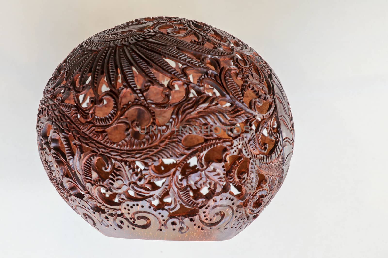 Close up ornamental shell for candle. Carved Souvenir from Coconut. Traditional handicraft on Bali, Indonesia. Hand carved ornaments with animal and plant motifs on the coconut shell. Mystical dragon.