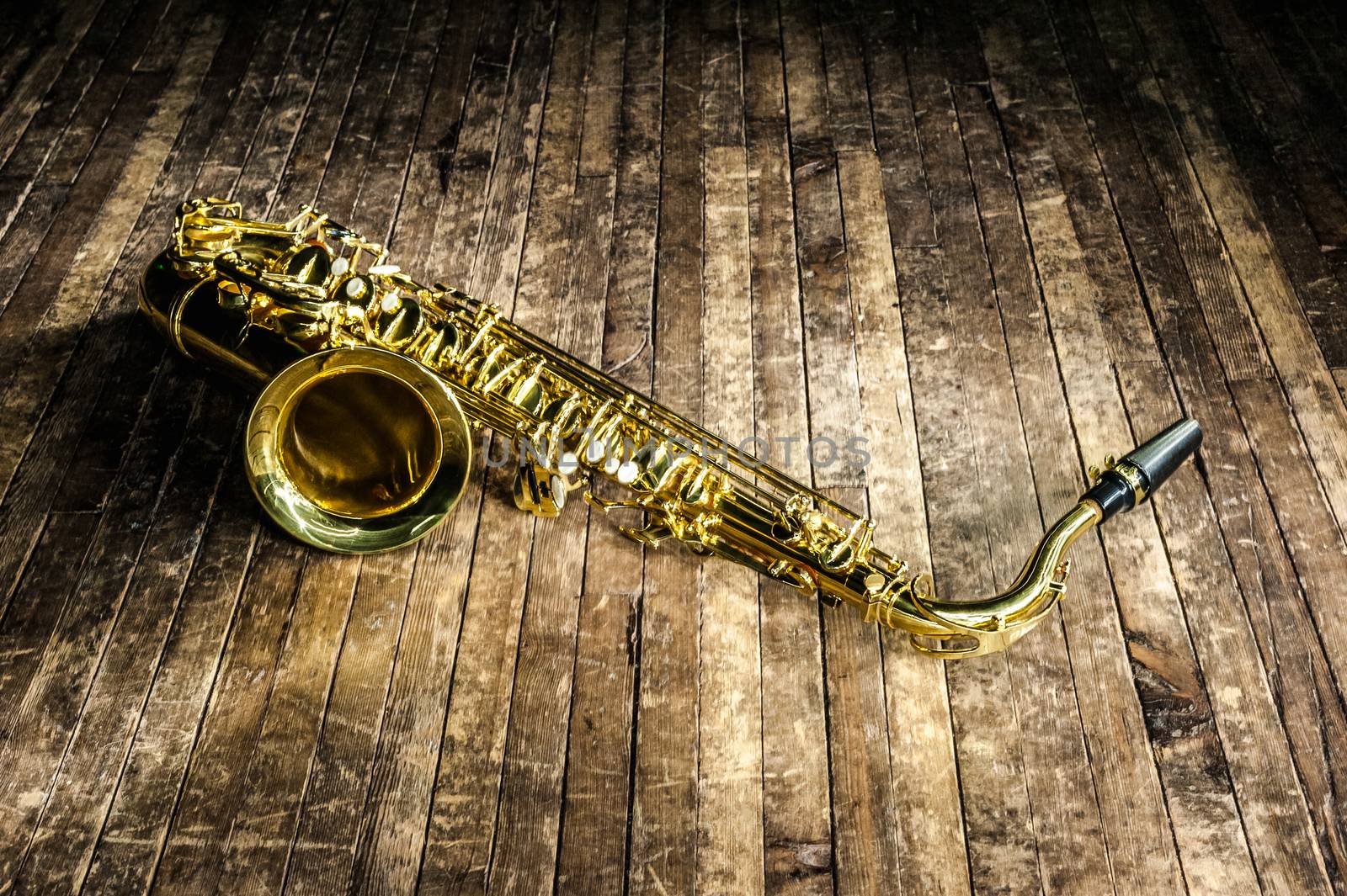 yellow jazz musical instrument saxophone lies on a wooden brown stage
