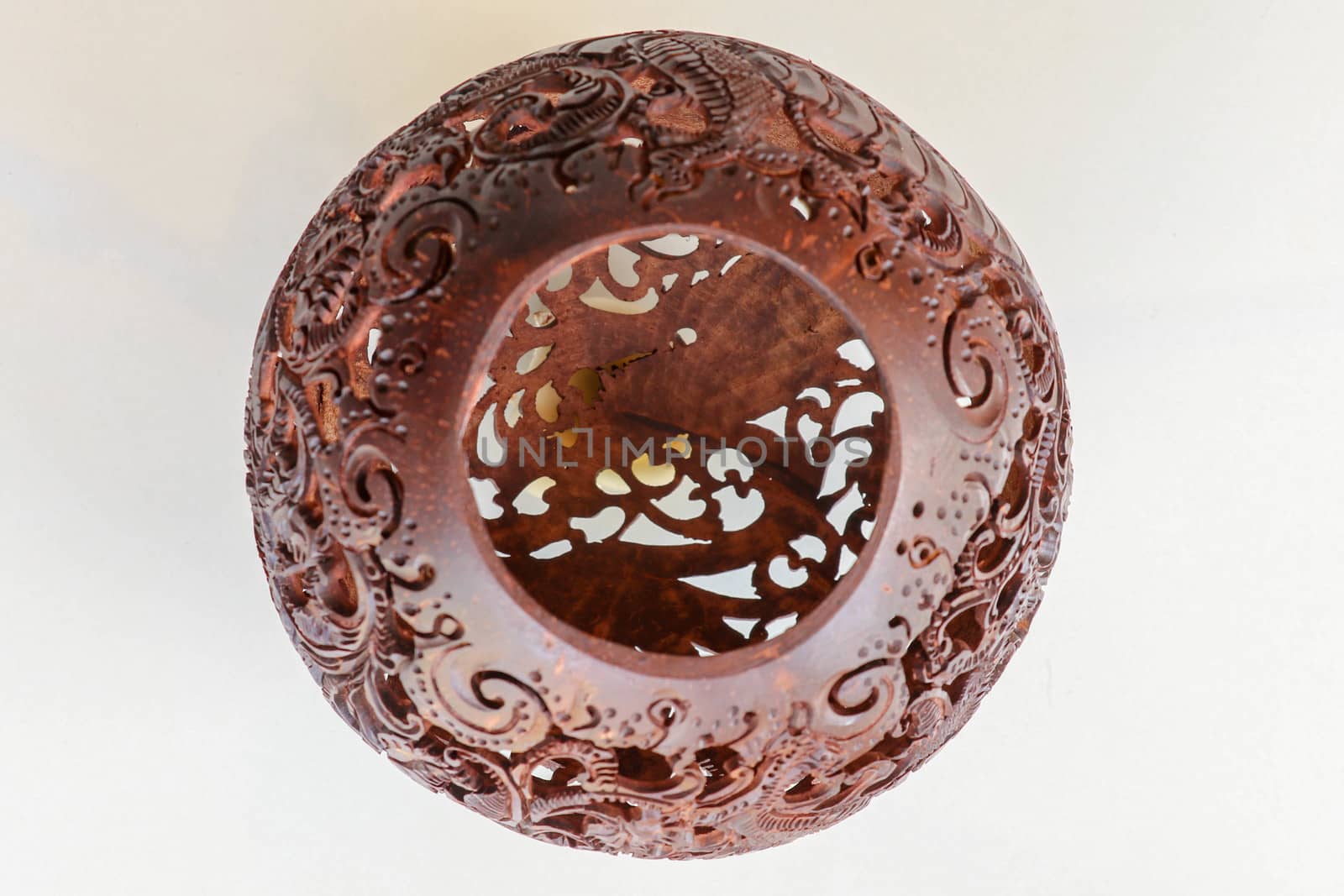 Close up ornamental shell for candle. Carved Souvenir from Coconut. Traditional handicraft on Bali, Indonesia. Hand carved ornaments with animal and plant motifs on the coconut shell. Mystical dragon.