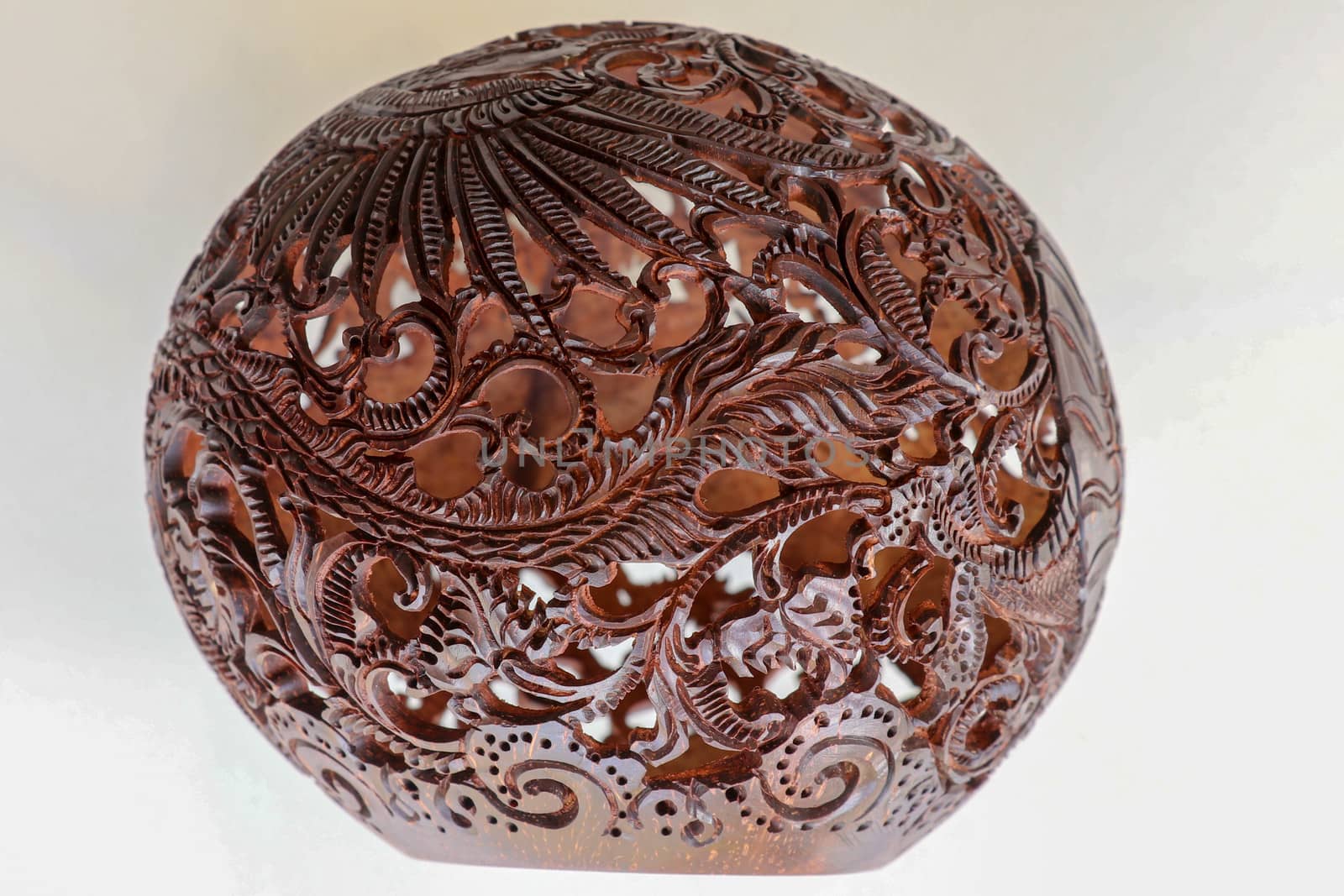 Close up ornamental shell for candle. Carved Souvenir from Coconut. Traditional handicraft on Bali, Indonesia. Hand carved ornaments with animal and plant motifs on the coconut shell. Mystical dragon.