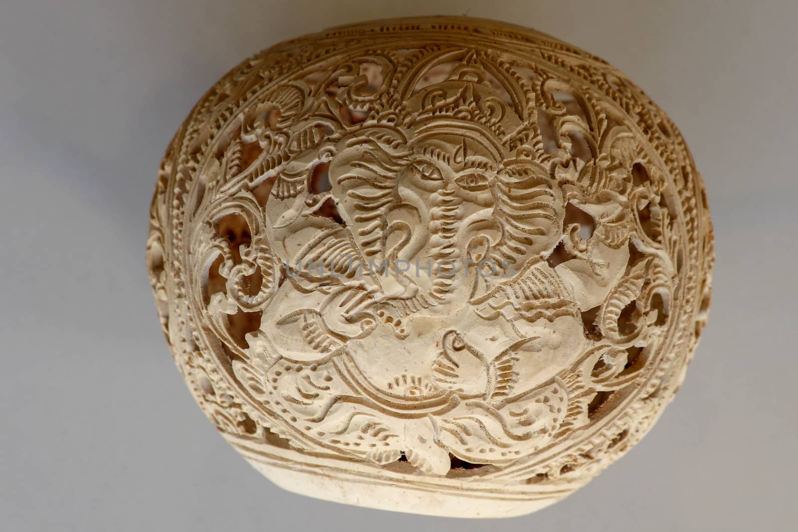 Close up of ornamental shell for candle. Hand carved decorative ornaments and motif of Hindu God Ganesha.Carved souvenir from white coconut. Traditional handicraft on Bali, Indonesia.