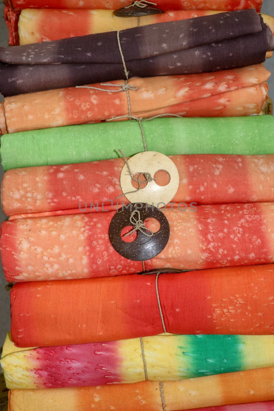 Batik cloth cloth for sale rolled up in market. Balinese art and culture. Close up of rolled colorful sarong. Colorful fabric rolls. Traditional Hindu clothing on Bali island. Sarung ready for sell.